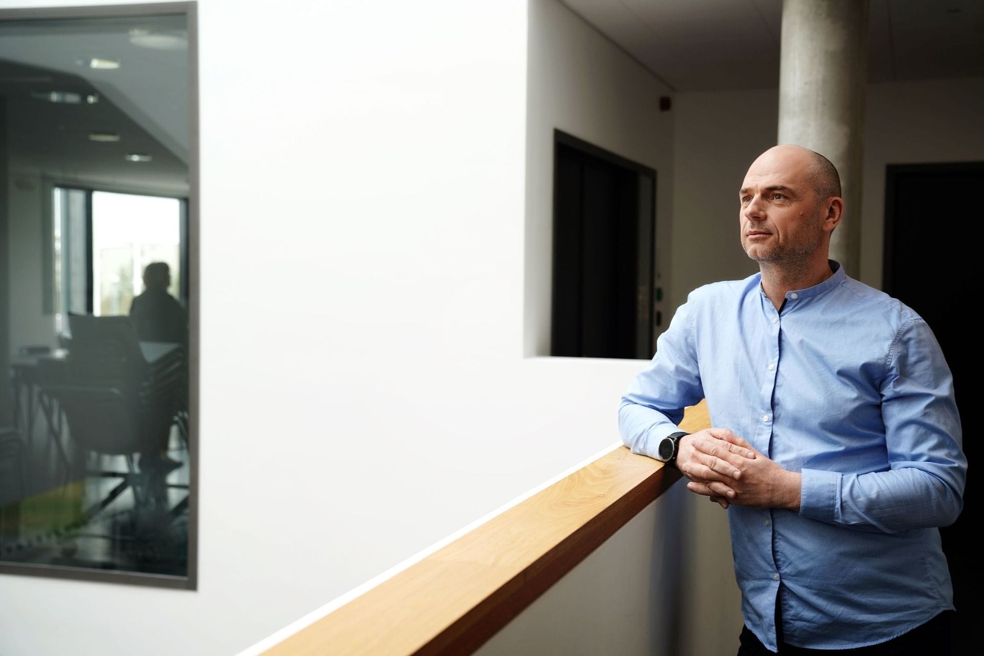 Maður stendur við handrið með spenntar greipar